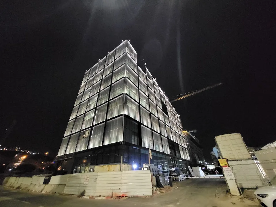 The glazed building lit at night, with grazing light along the floors