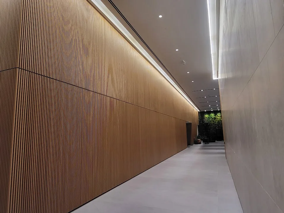 A lobby corridor with a timber-slat wall and cove lighting