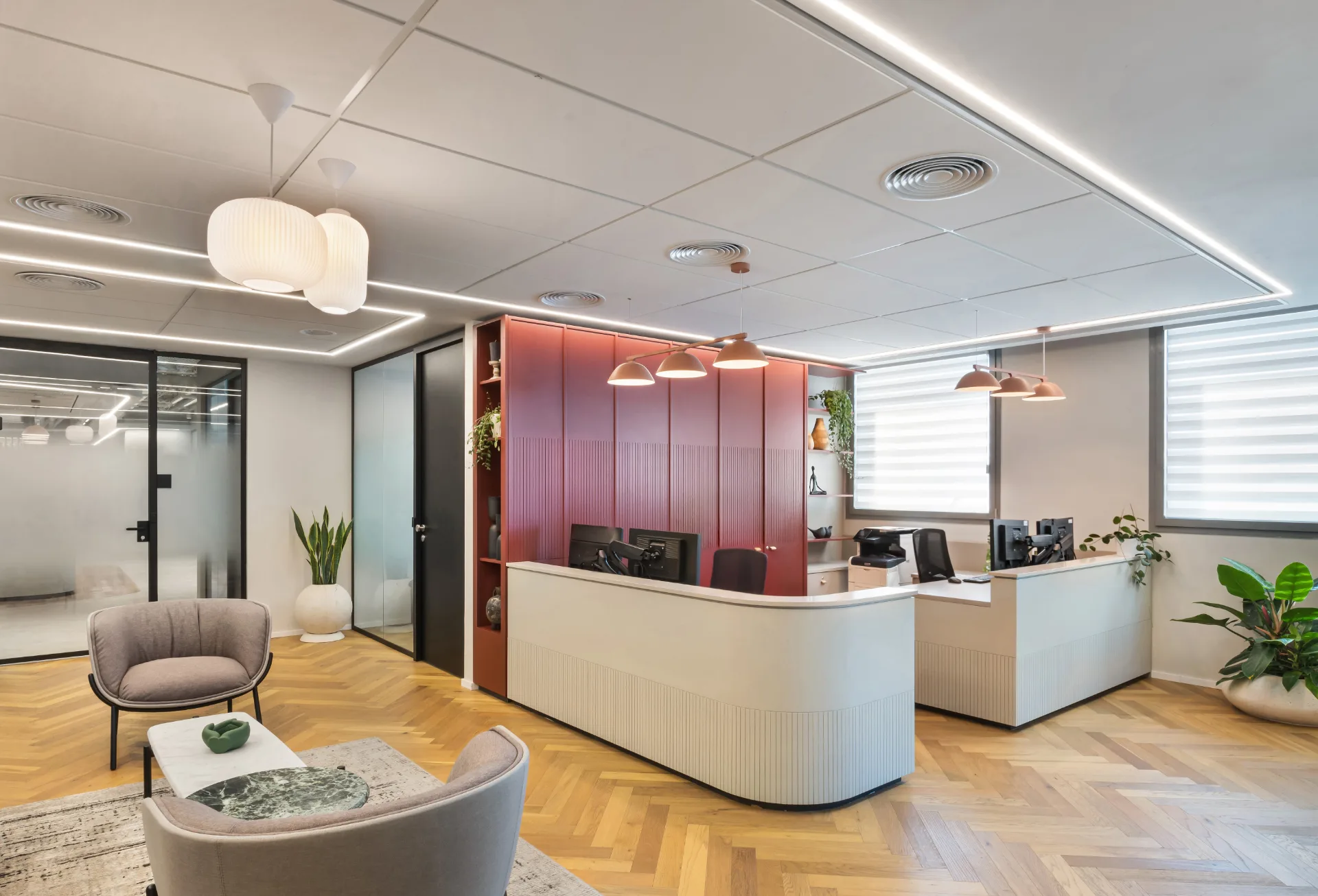 Reception desks against a red feature wall with linear lighting