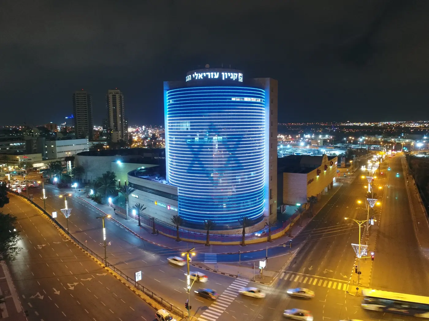 The round Azrieli HaNegev tower wrapped in blue LED bands at night