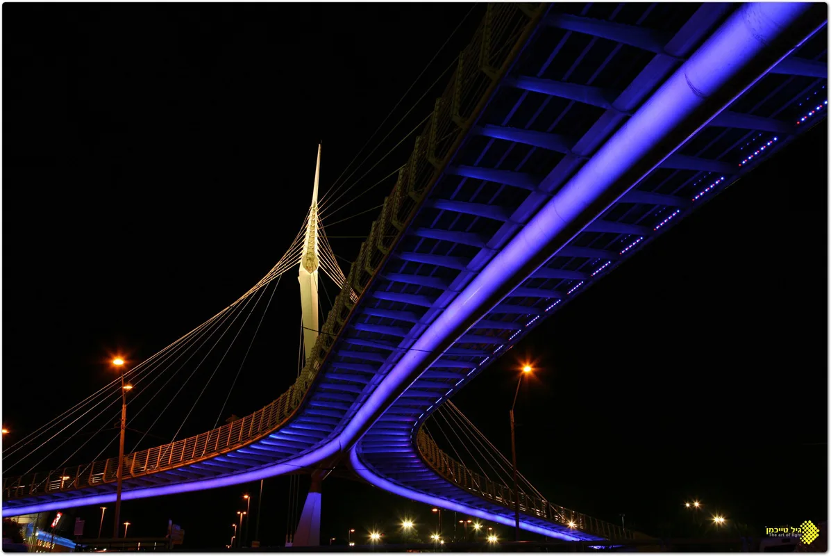 The violet-lit curve of the bridge from below