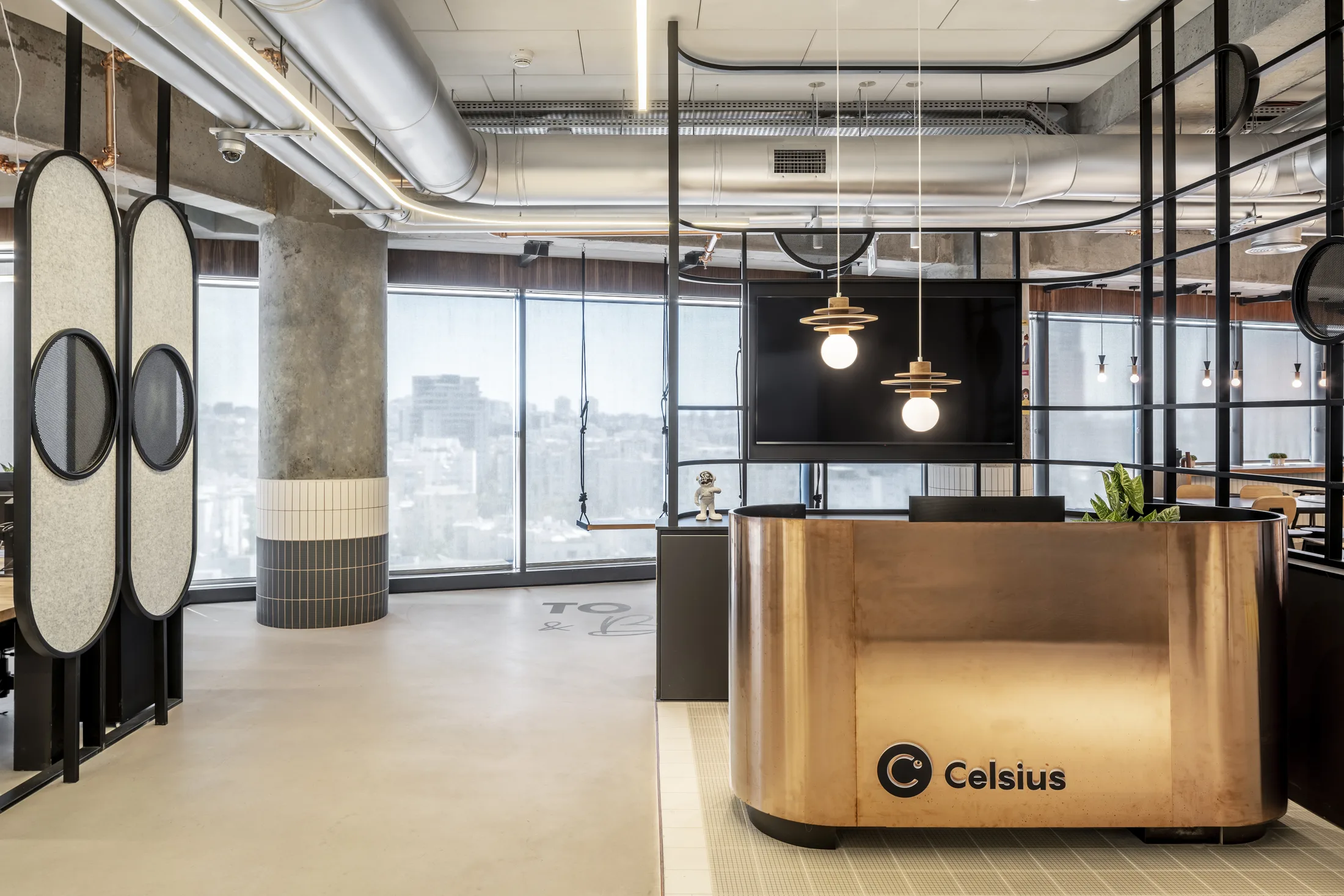 A copper-clad reception desk with globe pendants and a city view
