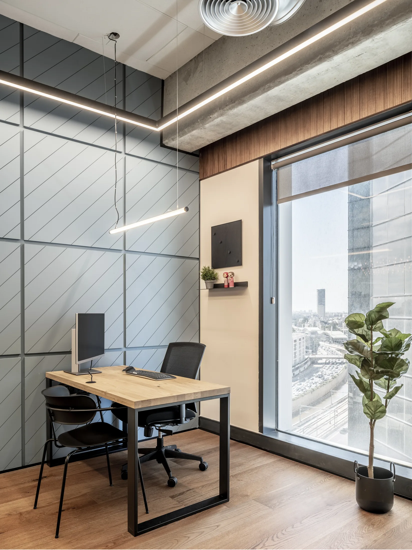 A private office with a suspended linear lamp and a window onto the skyline