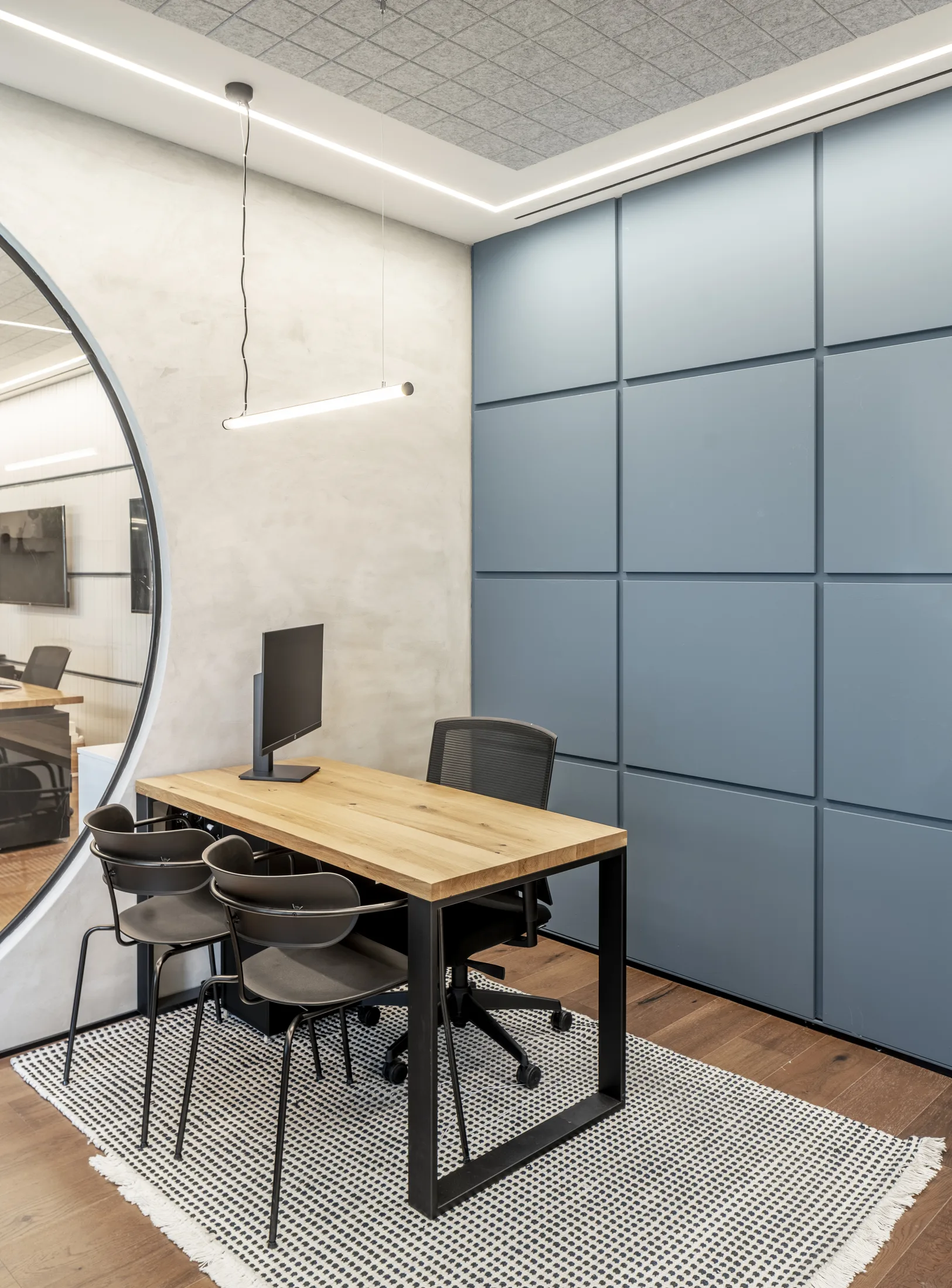 A meeting room with a suspended linear lamp and a blue acoustic wall