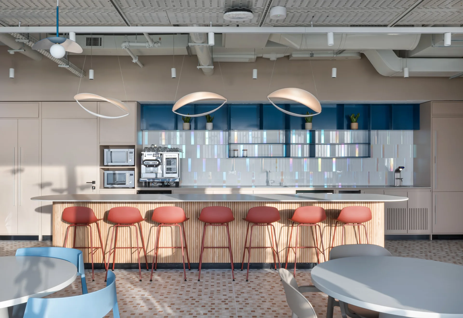Kitchen with an iridescent tile backsplash and pendants
