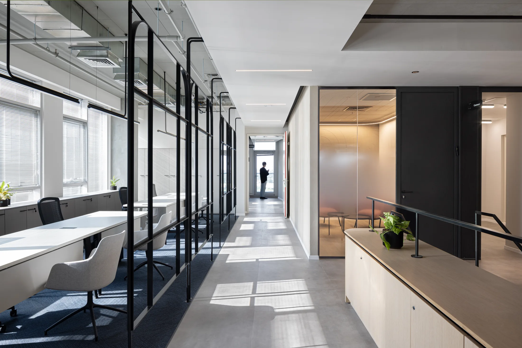 Office corridor beside open work areas and a glazed meeting room